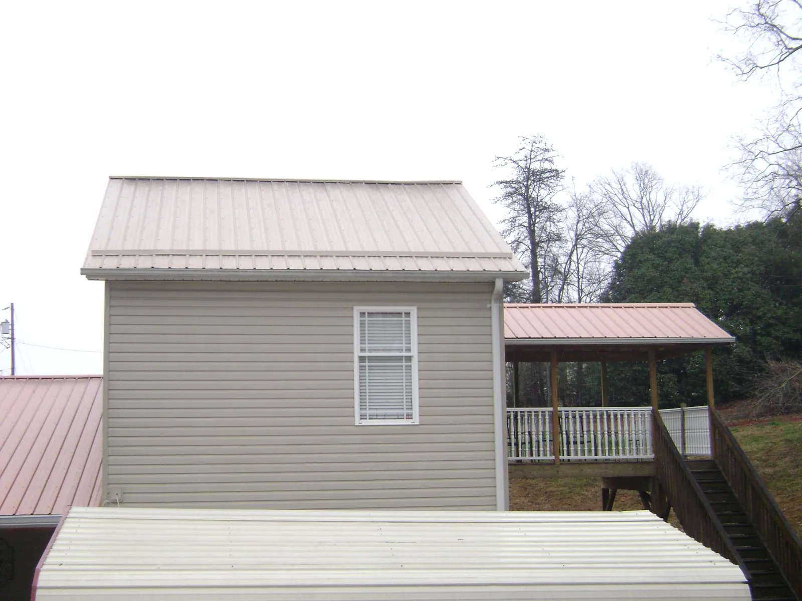 Tan metal roofs on a two story addition and attached porch, from a Roof Replacement job in Meridian